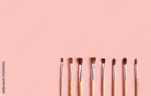 in close-up, the paint brushes lie side by side on a pink background with space for writing. artist's composition