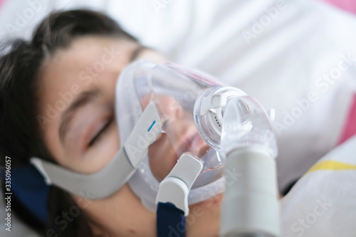 A woman sleeping in her bed with a ventilator