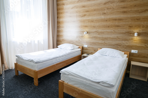 Large bright room in a hostel with three beds. White bedding photo