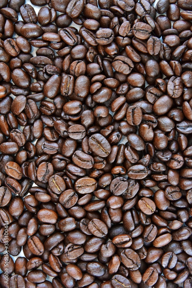 Obraz premium Roasted Coffee beans background with selective focus. Arabica coffee seeds. Vertical position