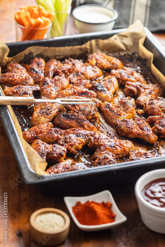 Grilled chicken wings in barbecue sauce in baking tray.