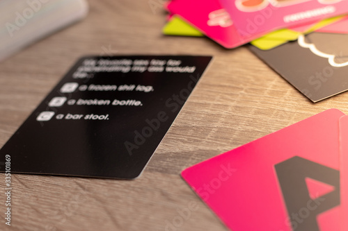 Black card representing a card board game. Answers blurred but barely visible. Multiple cards on the table, pink A in the corner. photo