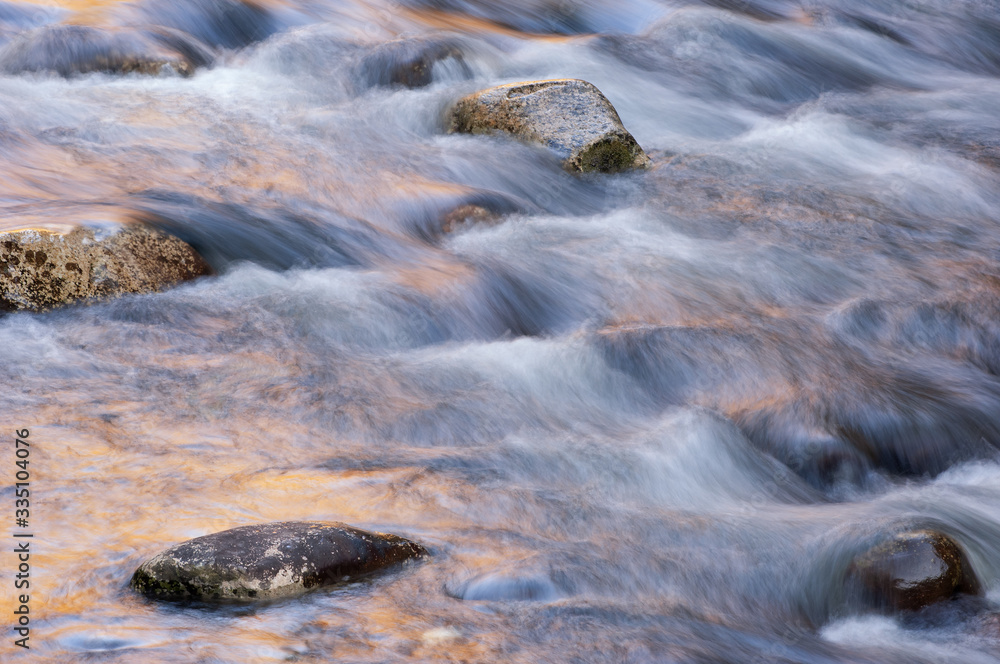 Obraz premium Landscape of the Little River captured with motion blur and aglow with reflected color from sunlit autumn foliage, Great Smoky Mountains National Park, Tennessee, USA