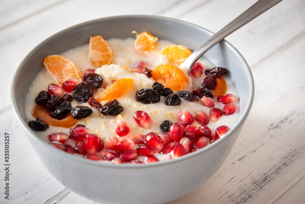 grey plate of oatmeal porridge with pieces of fruit on a white wooden background grey plate of oatmeal porridge with pieces of fruit on a white wooden background