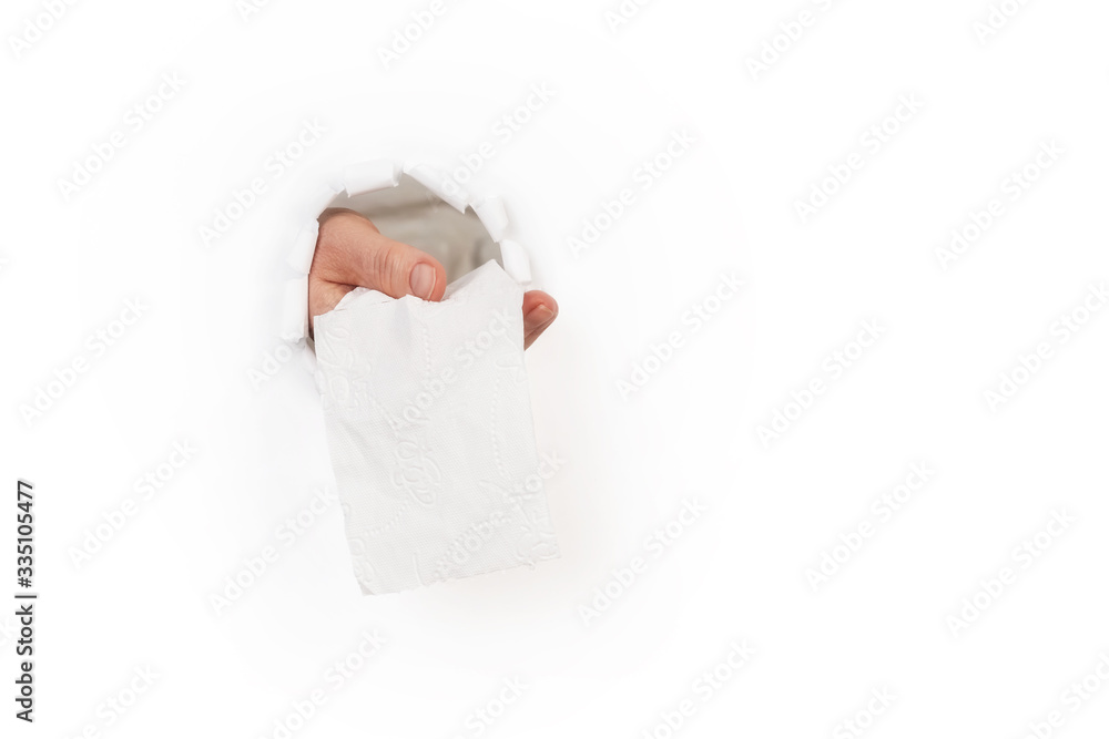 Obraz premium Hand delivers toilet paper through hole in the wall
