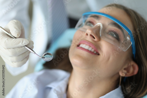 Dentist hold in hand mirror ready to examine female patient close-up