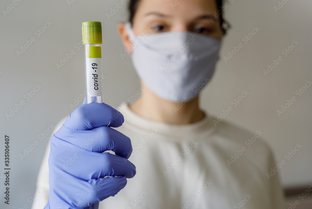 girl in a protective mask and gloves holds a flask for tests for coronavirus girl in a protective mask and gloves holds a flask for tests for coronavirus