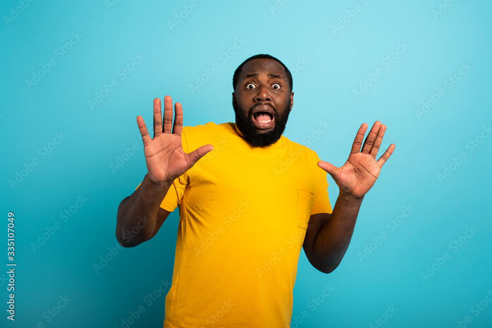 Fearful expression of a boy who is scared to catch the coronavirus. Cyan background. Fearful expression of a boy who is scared to catch the coronavirus. Cyan background.