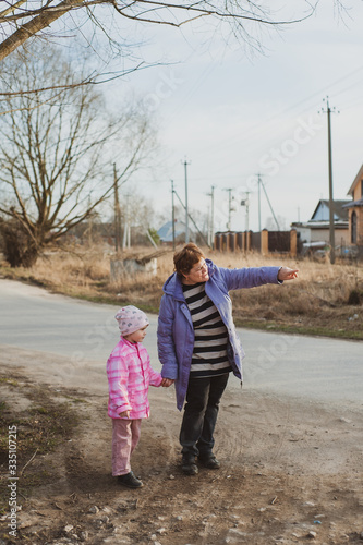 Wallpaper Mural Grandmother and granddaughter walk along a country road. A little girl and an adult woman walk together. Torontodigital.ca