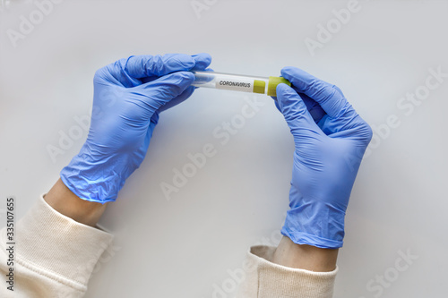hands in blue medical gloves hold a flask for virus tests