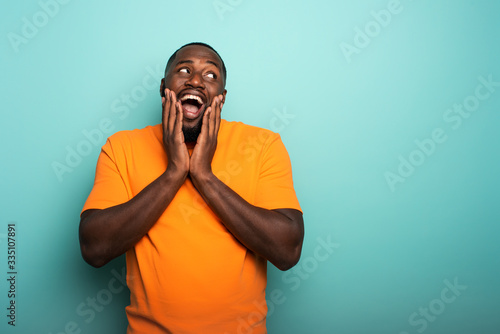 Joyful and happy afro guy over cyan background