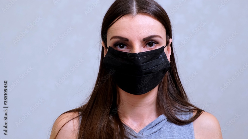 Female patient in a disposable cap puts on a black protective mask. Hygiene concept. prevent the spread of germs and bacteria and avoid infection with the crown virus Female patient in a disposable cap puts on a black protective mask. Hygiene concept. prevent the spread of germs and bacteria and avoid infection with the crown virus