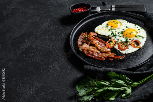 Fried eggs with bacon. Black background. Top view. Space for text