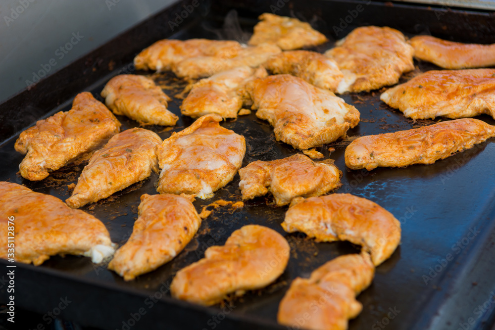 Many chicken breast grilling on gas grill outdoor.