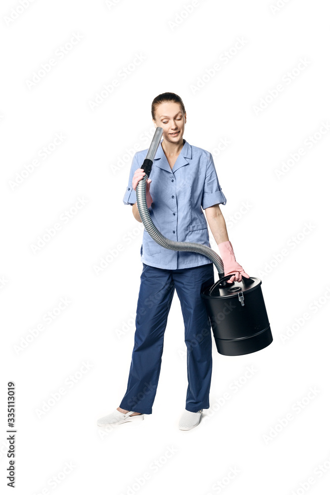 Young beautiful woman in a maid costume smiling and getting ready for vacuuming, isolated on a white background. She fools around and looks into the pipe. Young beautiful woman in a maid costume smiling and getting ready for vacuuming, isolated on a white background. She fools around and looks into the pipe.