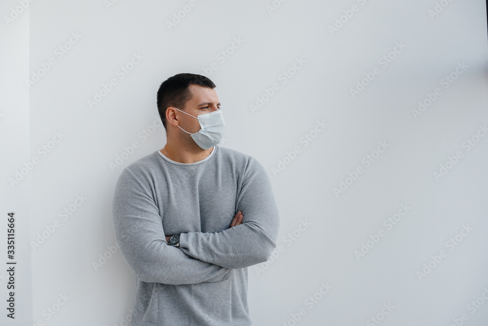 A young man stands on a gray background wearing a mask during a quarantine with free space. Quarantine in the mask A young man stands on a gray background wearing a mask during a quarantine with free space. Quarantine in the mask