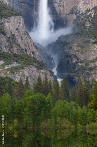 Spring landscape of Yosemite Falls captured with motion blur and with reflections in the flooded Merced River, Yosemite National Park, California, USA