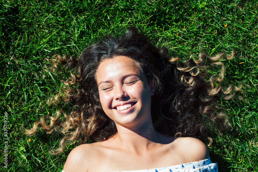 young cute summer girl on green grass outside relaxing smiling close up sunny vacation, lifestyle real people concept young cute summer girl on green grass outside relaxing smiling close up sunny vacation, lifestyle real people concept
