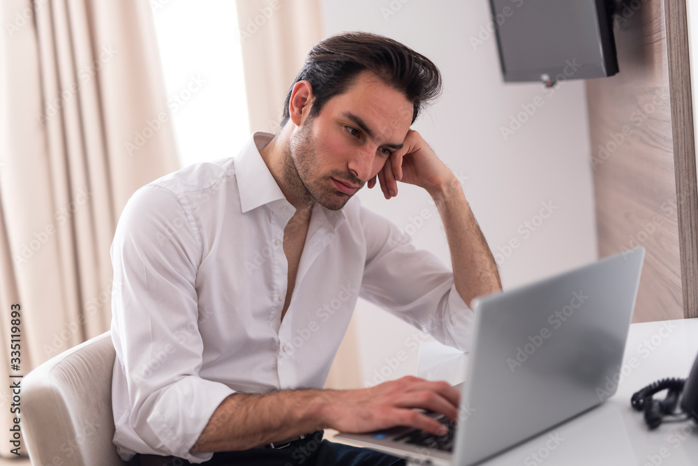 Handsome businessman sitting in his room with computer on the table and looking some emails Handsome businessman sitting in his room with computer on the table and looking some emails