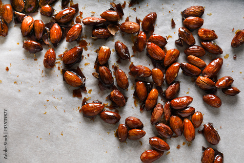Glazed almonds on parchment on a beige background in a modern style.