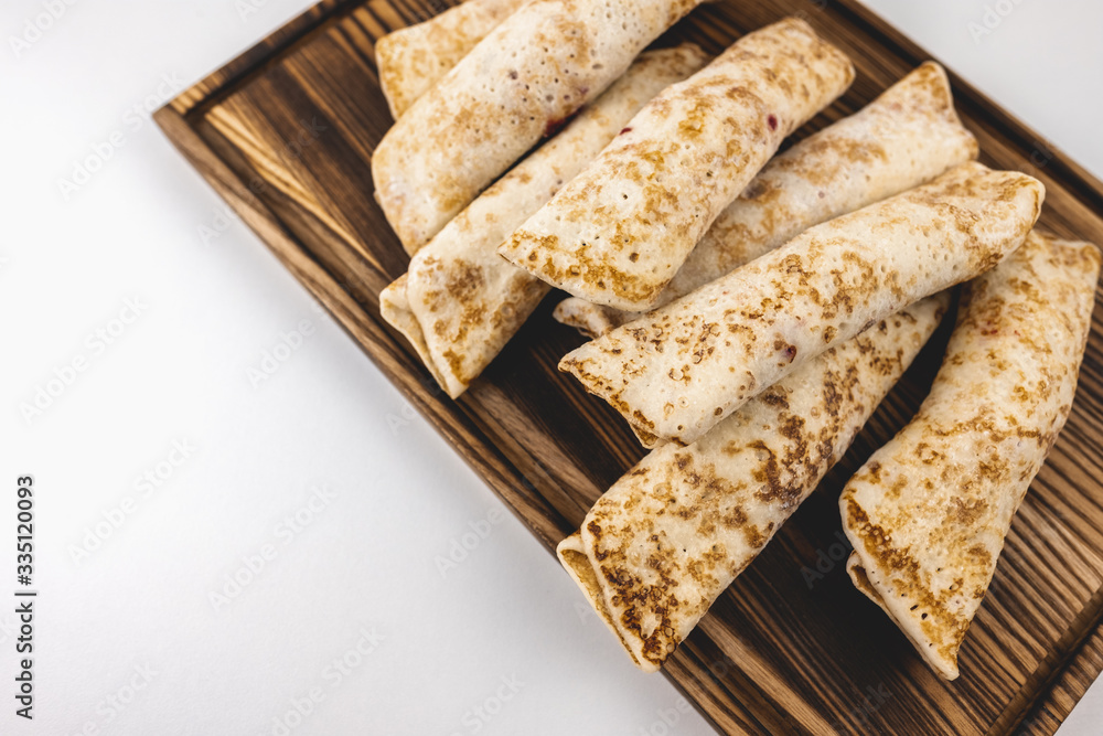 Frozen stuffed pancakes on a wooden board isolated on white background. Frozen stuffed pancakes on a wooden board isolated on white background.