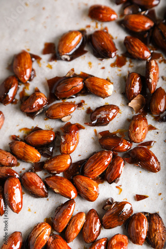 Glazed almonds on parchment on a beige background in a modern style.