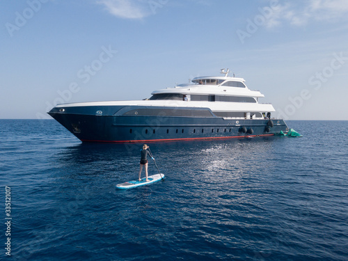 Girl on paddle board close to a luxury yacht © Антон Яковлев