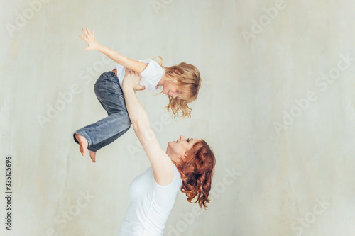 Stay Home Stay Safe. Young mother holding her child. Woman and little girl relaxing in white bedroom near windiow indoors. Happy family at home. Young mom playing whith her daughter. photo