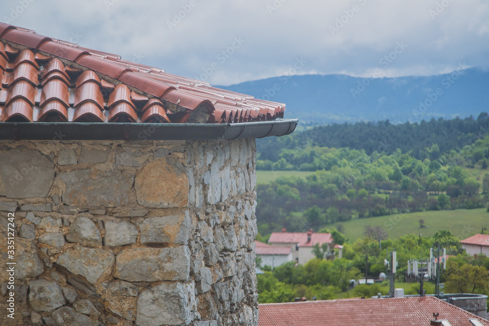 Detail of one of the typical Karst houses in Stanjel in Slovenia on a cloudy spring day, looking through window towards the house and rainy scenery