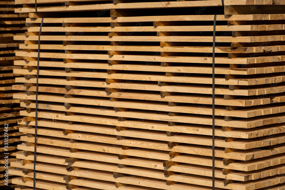 Warehouse for sawing boards on a sawmill outdoors. Timber mill, sawmill. Storage of planed wooden boards. Piles of wooden boards in the sawmill. Planking. Industry. Warehouse for sawing boards on a sawmill outdoors. Timber mill, sawmill. Storage of planed wooden boards. Piles of wooden boards in the sawmill. Planking. Industry.