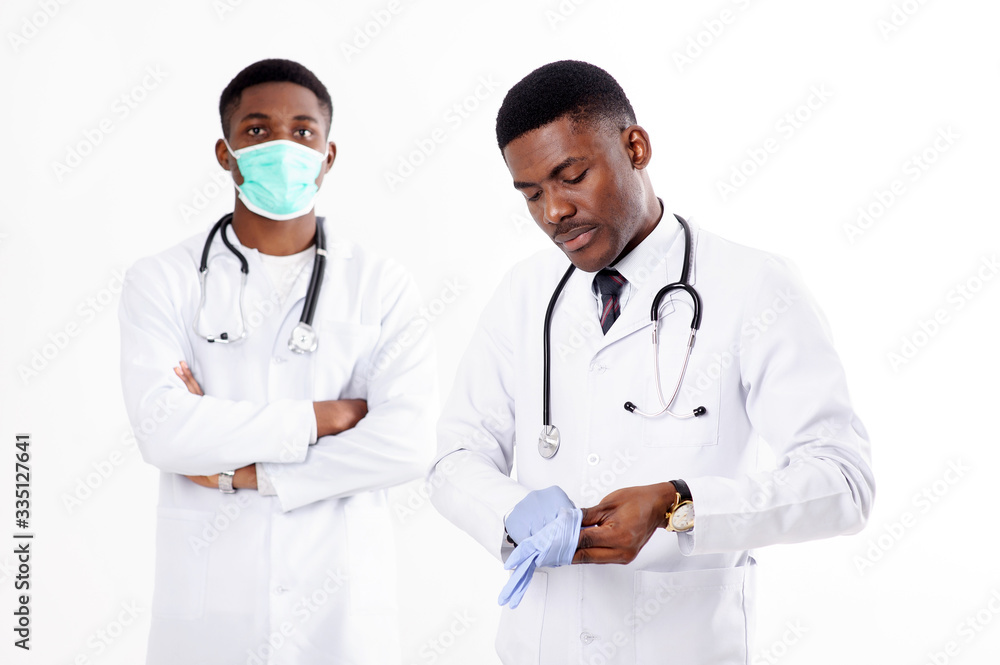 Two young african doctors on an isolated white background with a phonendoscope. One of them with mask. Two young african doctors on an isolated white background with a phonendoscope. One of them with mask.