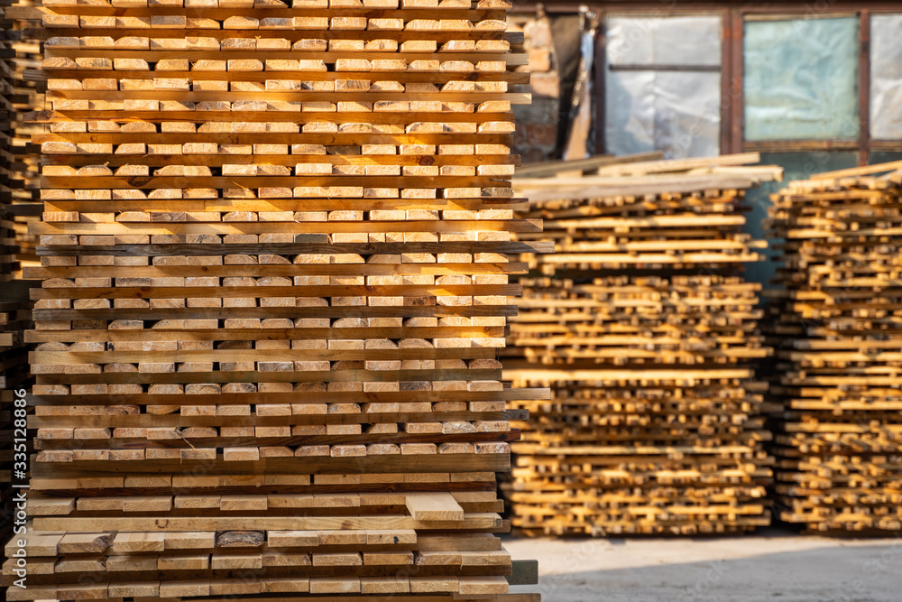 Warehouse for sawing boards on a sawmill outdoors. Timber mill, sawmill. Storage of planed wooden boards. Piles of wooden boards in the sawmill. Planking. Industry. Warehouse for sawing boards on a sawmill outdoors. Timber mill, sawmill. Storage of planed wooden boards. Piles of wooden boards in the sawmill. Planking. Industry.