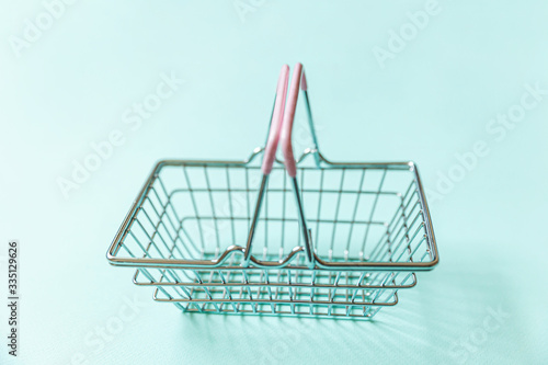 Small empty supermarket grocery shopping basket toy isolated on blue pastel colorful trendy background. Copy space. Sale buy mall market shop online shopping consumer concept.