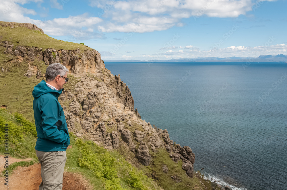 Man with sporty look observing the cliff and the view from Lealt Fall view point, Isle of Skye, Scotland. Concept: travel to Scotland, Scottish landscapes
