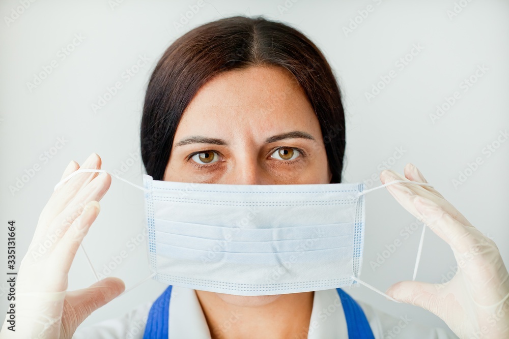 Tired, beautiful female doctor in a protective mask looks at us close-up. Protection against coronavirus Covid-19. Tired, beautiful female doctor in a protective mask looks at us close-up. Protection against coronavirus Covid-19.