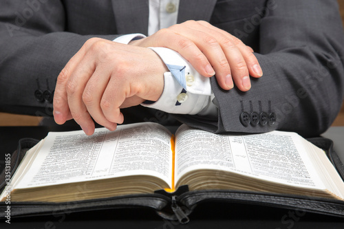 male hands lie on an open holy bible close up. the search for God and the study of the book