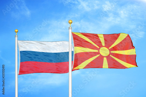 Russia and North Macedonia two flags on flagpoles and blue cloudy sky
