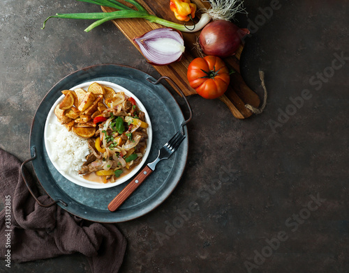 Peruvian dish Lomo saltado, made of beef tenderloin with red onion, yellow chili, tomatoes, with potato fries and rice. copy space