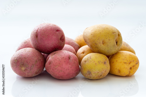 Close up of red and yellow bite size potatoes over white background