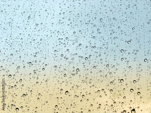 Beautiful raindrops on window glass with sunset in background