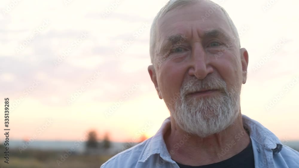 Elderly man with a gray beard at sunset in field, concept of emotions Elderly man with a gray beard at sunset in field, concept of emotions