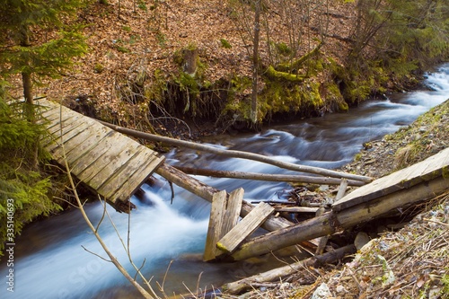 river Pylypets with fast current, a broken wooden bridge in the forest, fallen leaves and driftwood on banks of the creek, Carpathian Mountains in Transcarpathia, nature protection and ecology concept photo