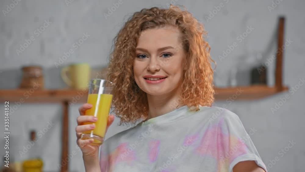 Smiling woman drinking orange juice in kitchen Smiling woman drinking orange juice in kitchen