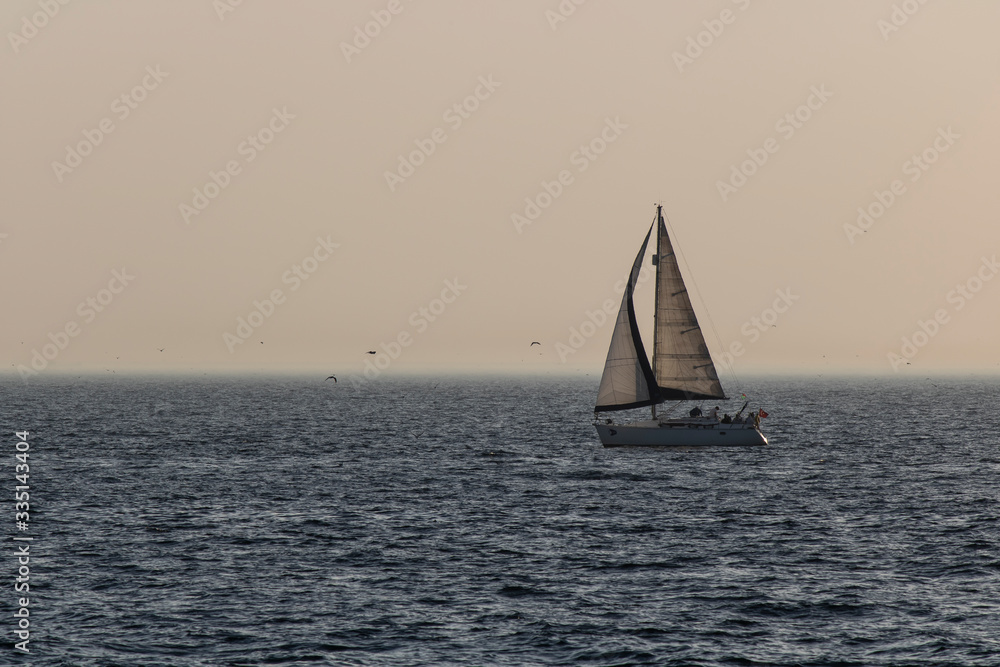 Sailboat floating on the sea. Photographed at sunset.
