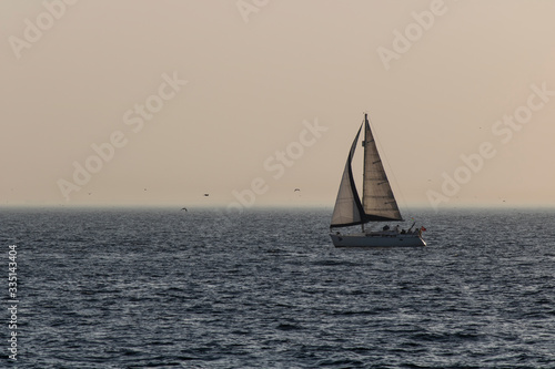 Sailboat floating on the sea. Photographed at sunset.
