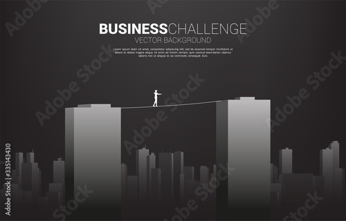 Silhouette of businessman walking on rope walk way across building.Concept for business risk and challenge in career path