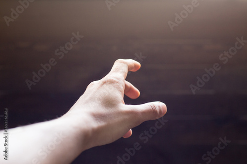 hand reaching out POV shot on a dark wooden background 