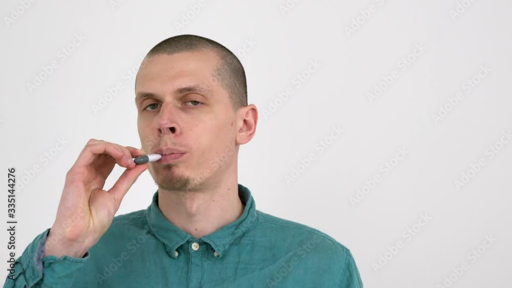 Man puts a digital thermometer under his tongue to measure temperature of his body. Oral method