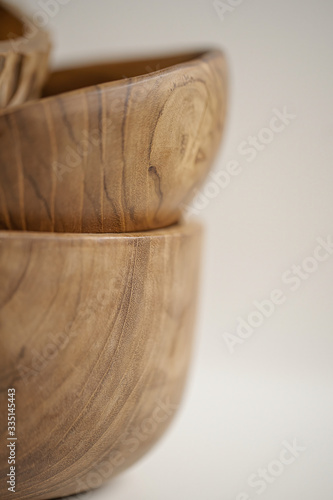 Wooden utensils for food on a white isolated background. Hand-made plates stand on top of each other. Close-up. Empty round tray, natural wood plate. Eco-friendly cookware.