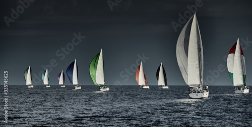 Fotografie Sailboats compete in a sailing regatta at sunset, sailing race, reflection of sa